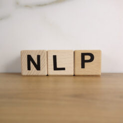 Programmazione neuro linguistica: cubi di legno con la sigla "NLP" in evidenza, rappresentano le basi della PNL.